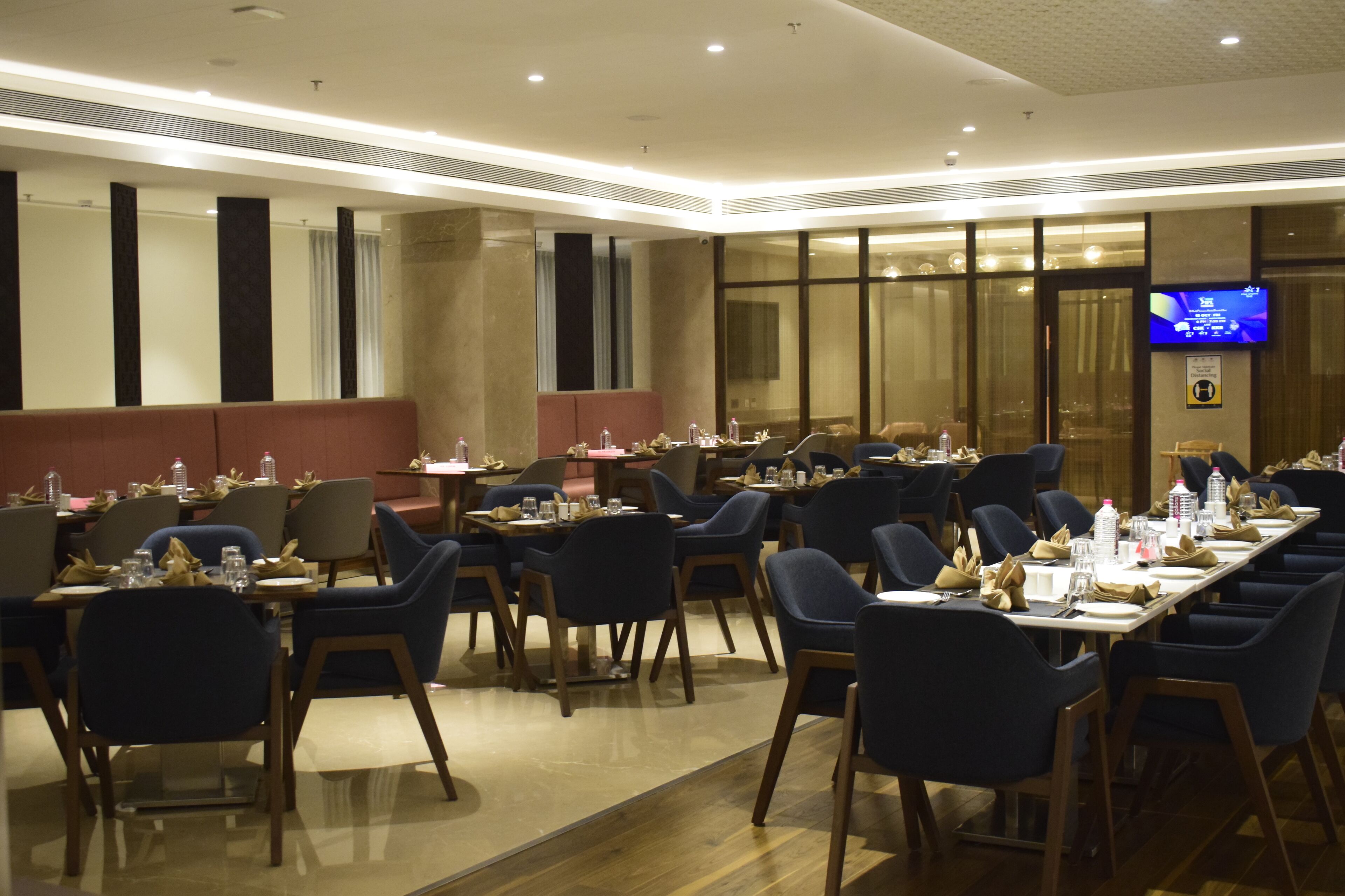 A hotel dining area with multiple tables set for guests, equipped with chairs, water bottles, and napkins.
