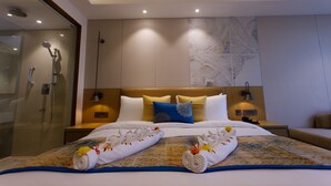 Habitación de hotel con una cama grande, cabina de ducha de vidrio y un adorno en la pared.