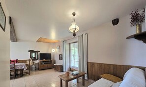 Ein Wohnzimmer mit Holzboden, einem Fernseher, einem Tisch und einem Sofa.