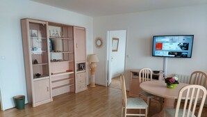 Ein Essbereich mit Holztisch und Stühlen, einem an der Wand montierten Fernseher und einer Vitrine.