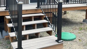 A wooden building with a black door, a set of wooden stairs with a black railing, and a green bench at the bottom. - Salmon Gathering Place sleeps 35 + perfect for reunions.retreats.events (Salmon)