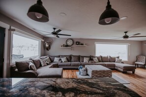 Una sala de estar moderna con un amplio sofá modular, una mesa de centro de madera y un ciervo decorativo en la pared.