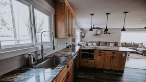 A kitchen with wooden cabinets, a granite countertop, a sink, and a built-in oven. - Salmon Gathering Place sleeps 35 + perfect for reunions.retreats.events (Salmon)