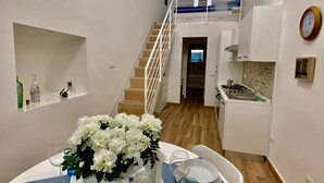 Ein Essbereich mit einem Tisch für zwei Personen, eine Treppe zu einer oberen Ebene und ein Küchenbereich.