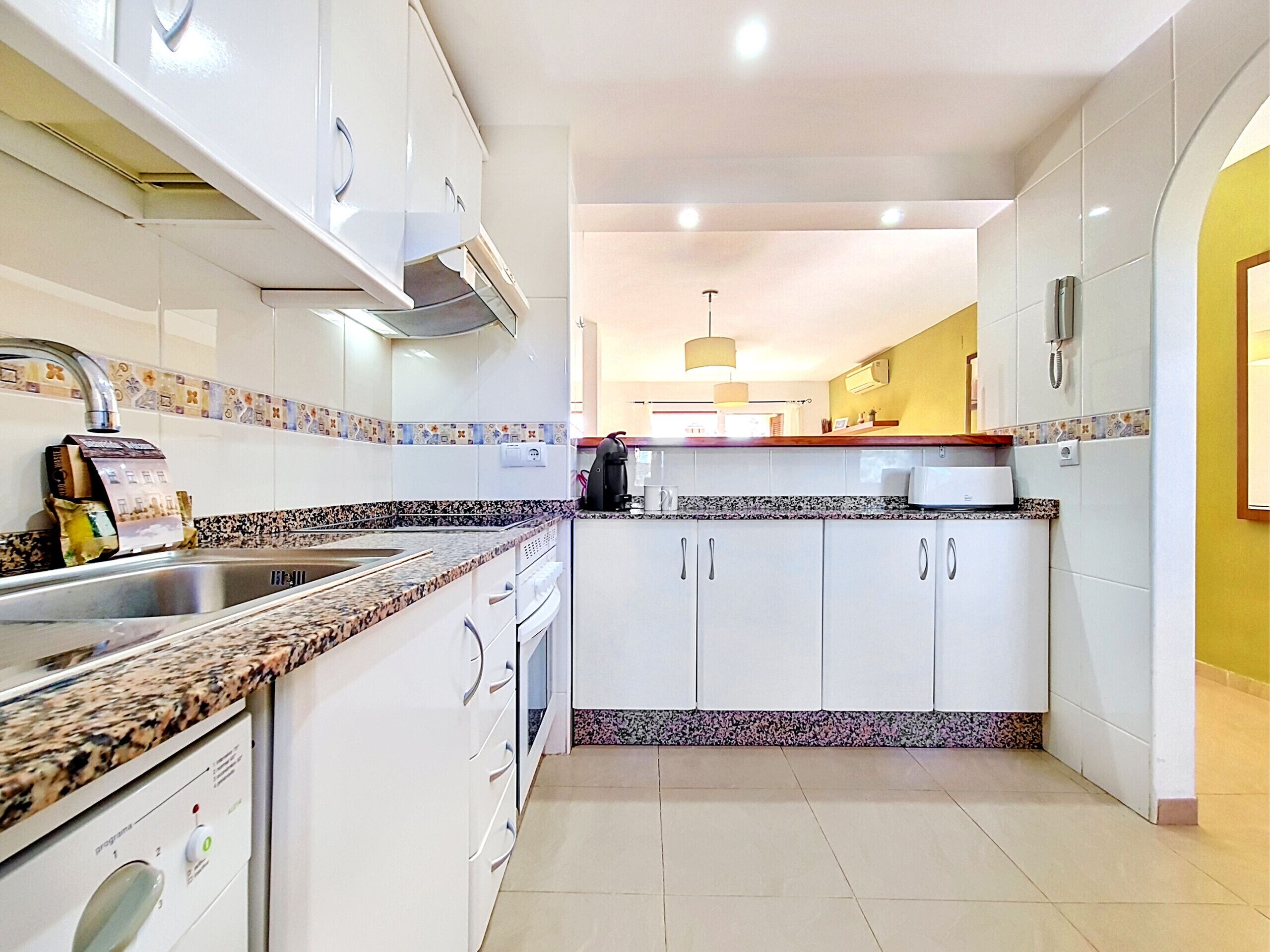 A modern kitchen with white cabinets, granite countertops, and a built-in oven.