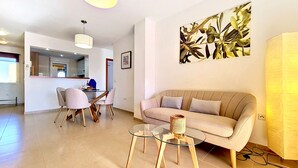 Ein modernes Wohnzimmer mit einer Couch, einem Glastisch und einem Essbereich mit Stühlen.