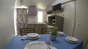A dining table set with plates, glasses, and cutlery, with a blue tablecloth. - Mobile home 2 rooms (Puerto Real)
