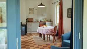 Une cuisine avec une table à manger, des chaises et une chaise bleue au premier plan.