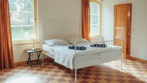 Une chambre à coucher avec un lit, deux fenêtres, une table de chevet et une porte.