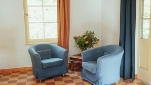 Une pièce avec deux fauteuils bleus, une table en bois et un vase de fleurs.