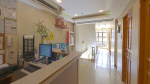 A reception area with a counter, computer, phone, and various informational posters. - Freemont Place (Parañaque)