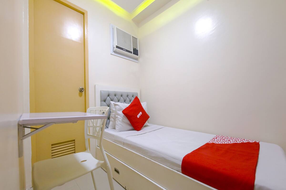 A small, clean room with a bed, a desk, and a chair.