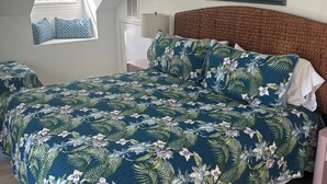 Ein Schlafzimmer mit einem großen Bett, einem Fenster mit Jalousien, einem Gemälde an der Wand und einem Holzboden.