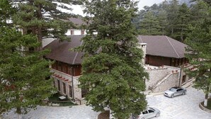 A building with a tiled roof, a stone facade, and a parking area with a car. - Llogora Tourist Village (Orikum)