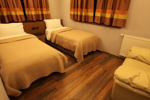 Una habitación pequeña y acogedora con dos camas individuales, suelo de madera y un radiador.