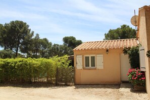 A small house with a tiled roof, a door with shutters, and a satellite dish.