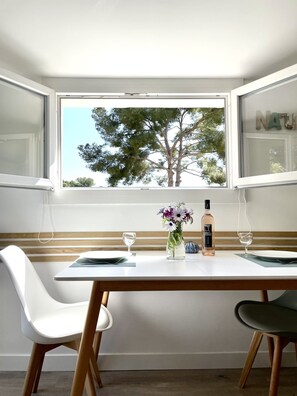 Un coin repas avec une table dressée pour deux personnes, un vase de fleurs et une bouteille de spiritueux.
