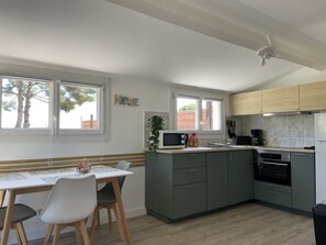 A modern kitchen with a dining area, featuring a built-in microwave, a coffee maker, and a sink.