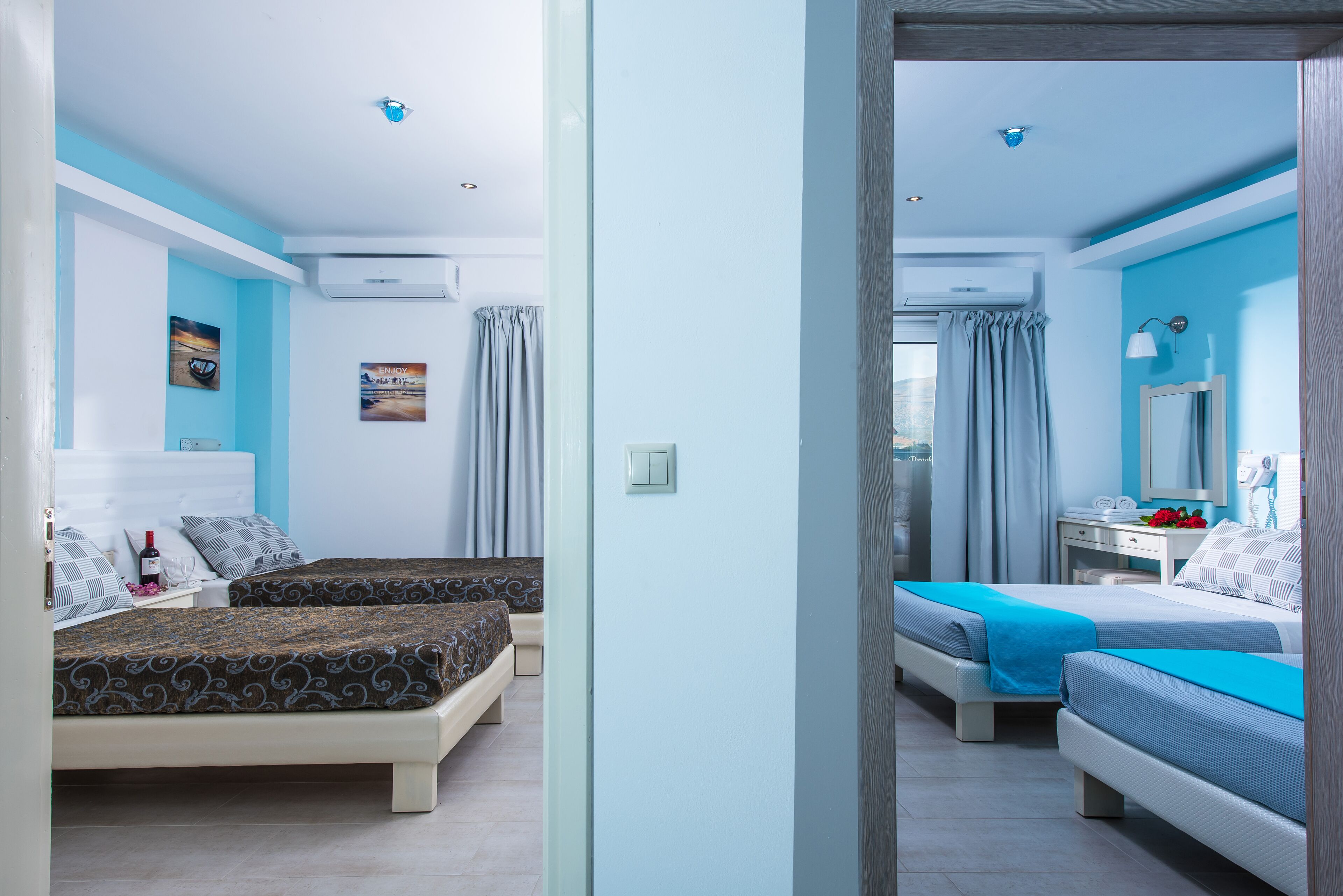 A hotel room with two beds, a desk with a mirror, and a window with curtains.