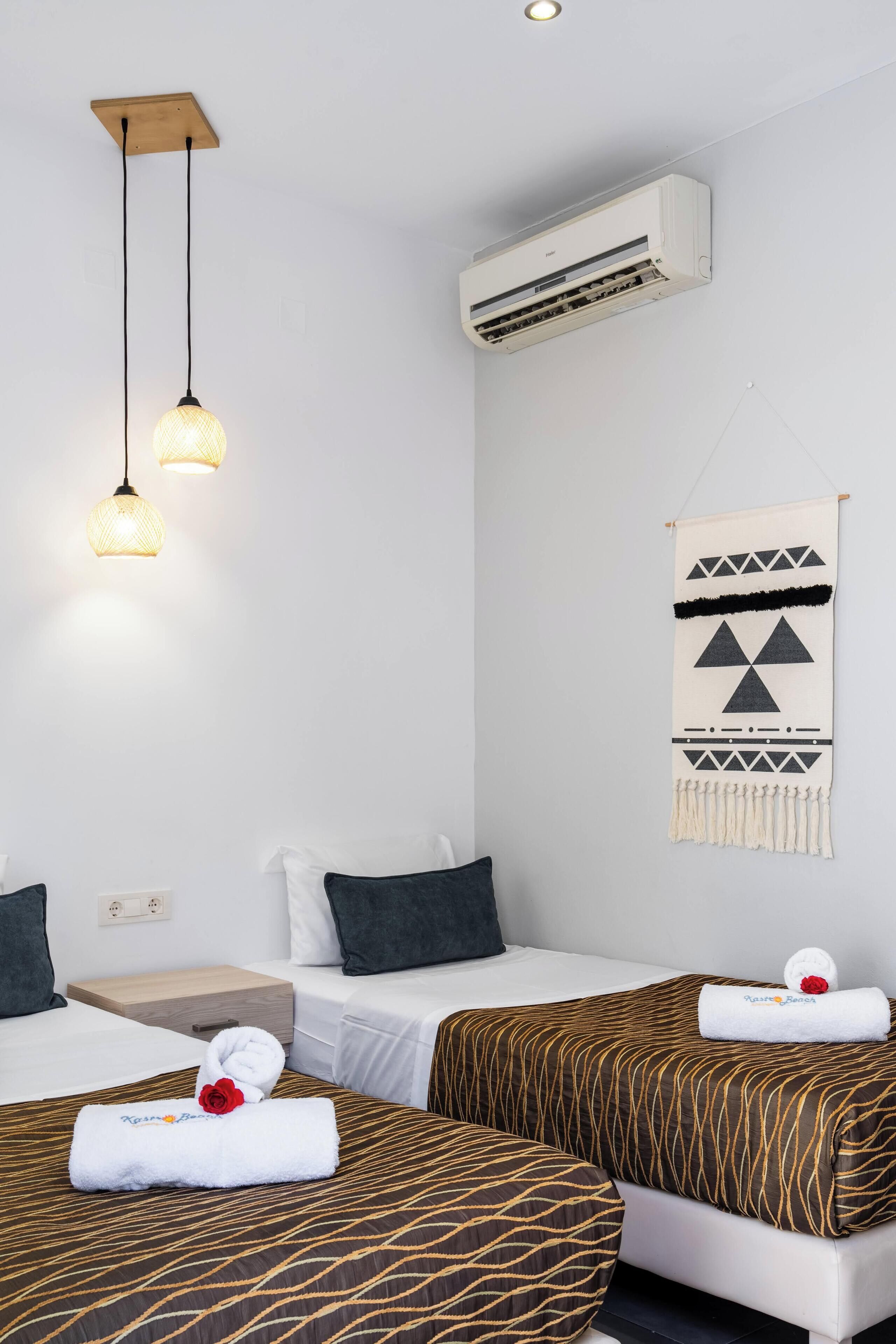 Habitación de hotel con dos camas, aire acondicionado instalado en la pared y un adorno decorativo en la pared.