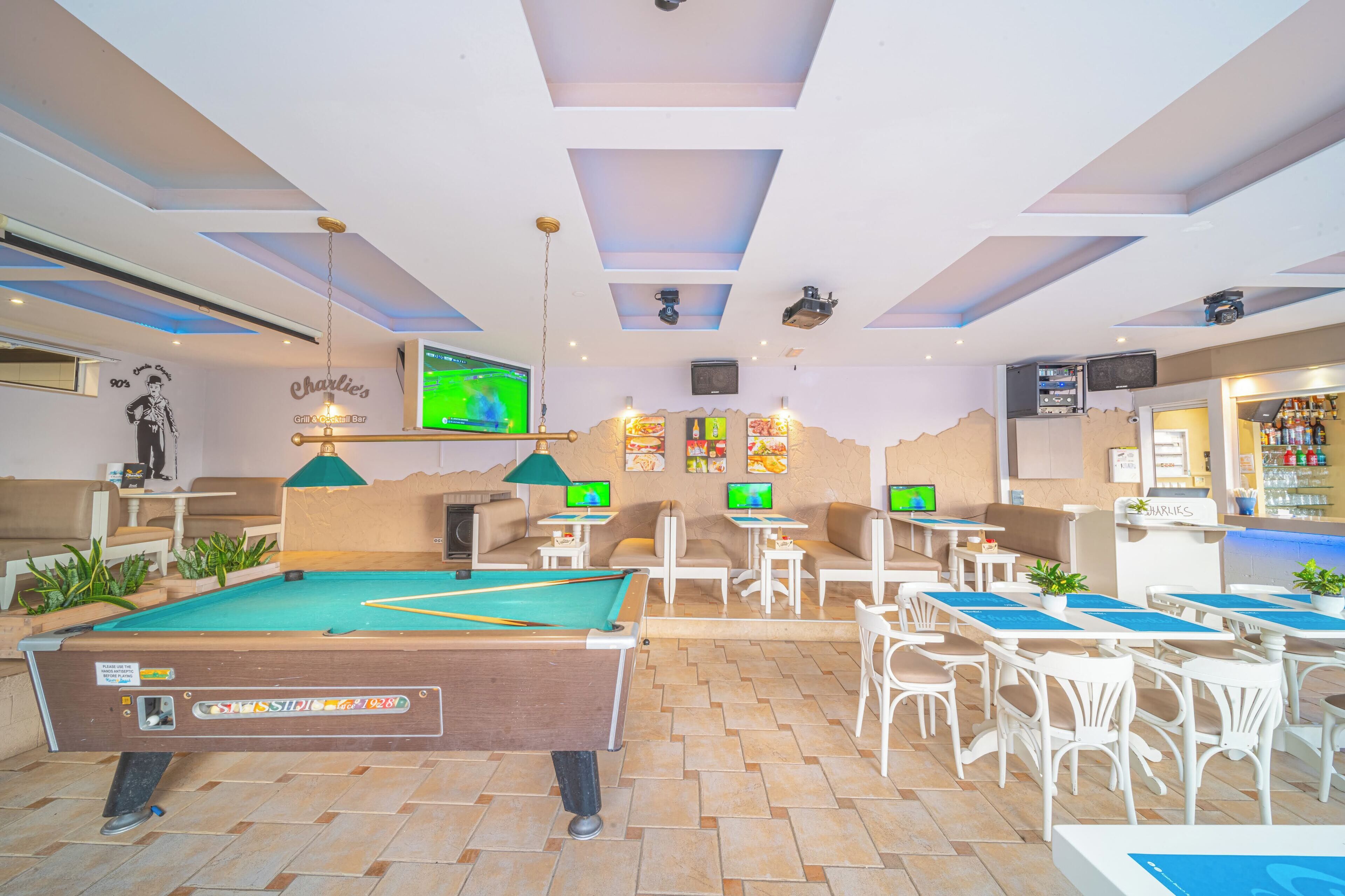 A pool table in a lounge area with multiple seating options and a bar.