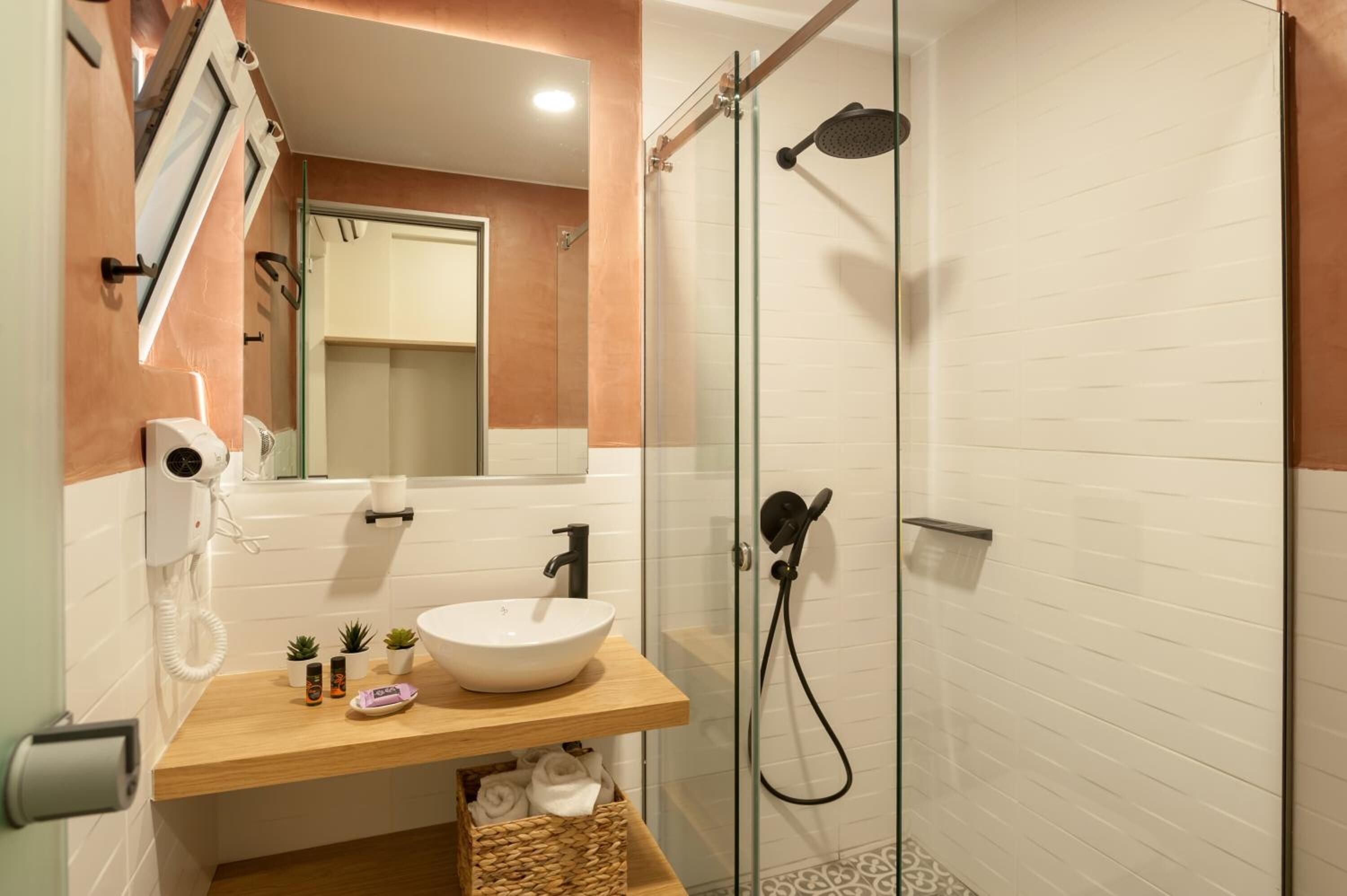 A modern bathroom with a glass shower enclosure, a white sink, and a wooden vanity.