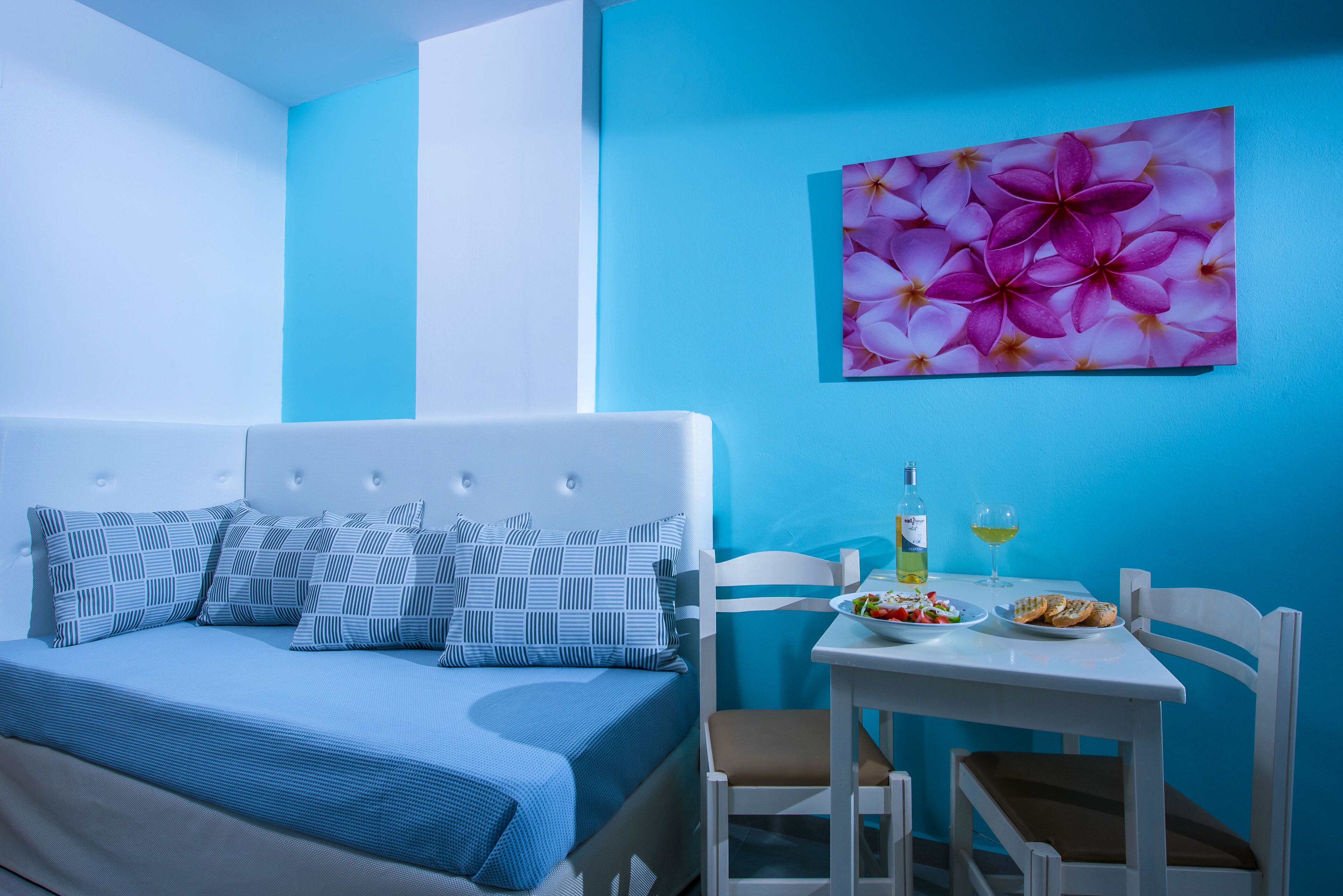 Ein Schlafzimmer mit einem Bett, einem Esstisch mit Stühlen, einer Olivenölflasche und einem Weinglas.