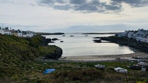 A coastal town with white buildings, a rocky shoreline, and boats in the water.