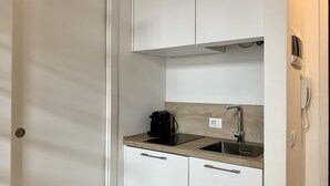 A compact kitchen with white cabinets, a black coffee maker, and a built-in sink.