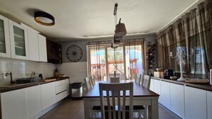 Een moderne keuken met witte kasten, een eettafel met stoelen, een klok en een raam met gordijnen.