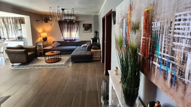 Een moderne woonkamer met een bank, salontafel en een groot abstract schilderij.