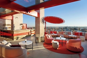Terraza en la azotea con zona de bar, asientos y vistas de la ciudad.