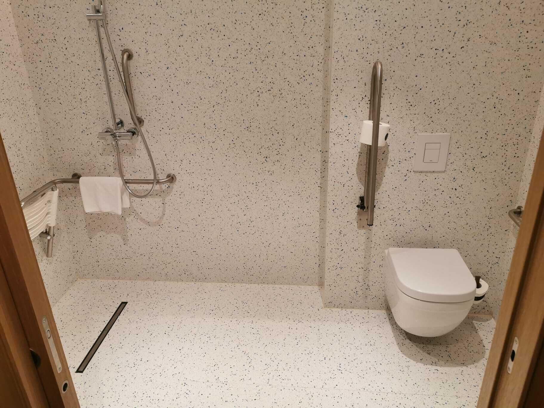 Un baño pequeño y funcional con ducha, inodoro y perchero para toallas.