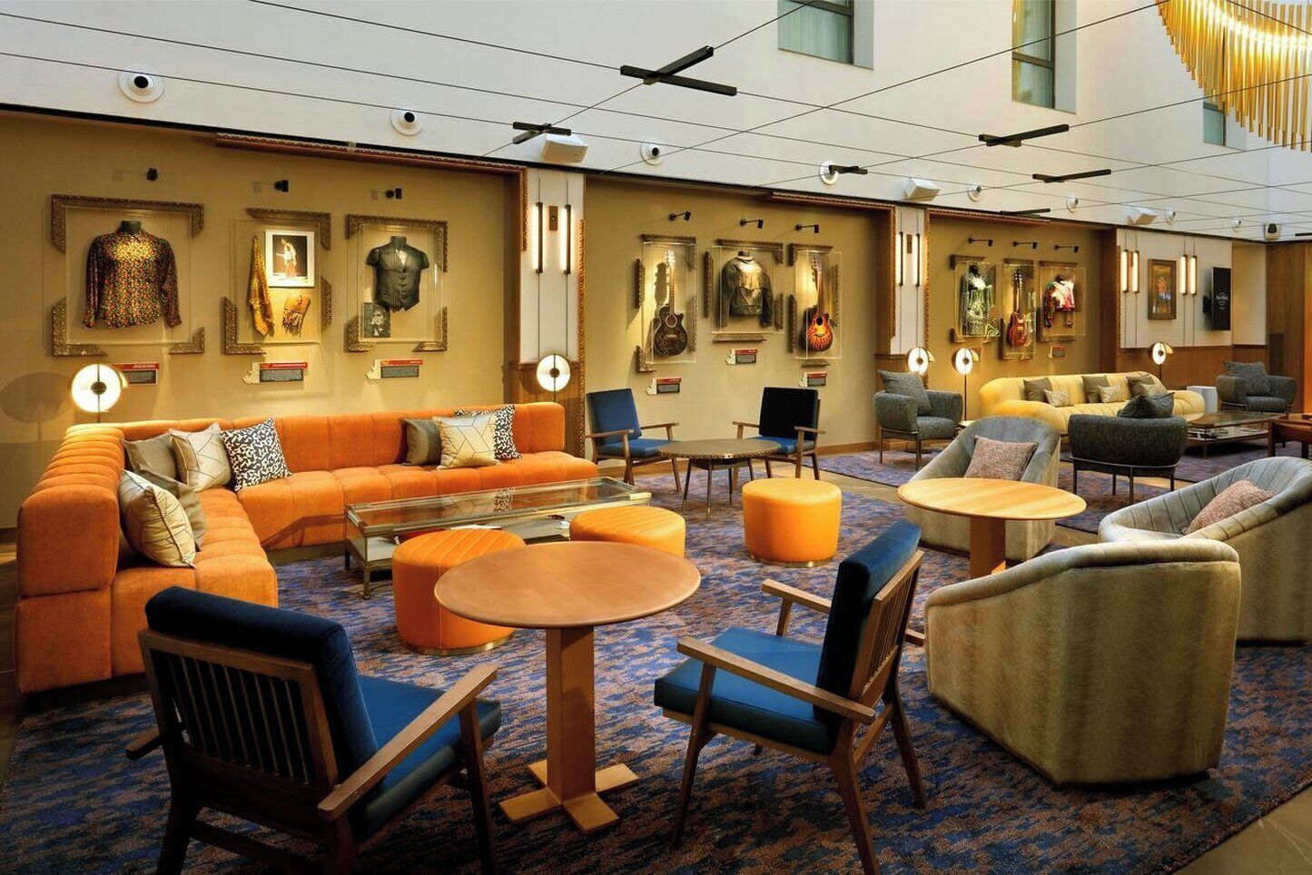 A spacious lobby with a large orange sofa, multiple seating areas, and a wall adorned with framed artwork.