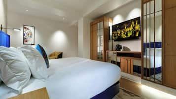 Una habitación de hotel moderna con una cama grande, un televisor de pantalla plana en la pared, un escritorio con una silla y un armario con puertas correderas.