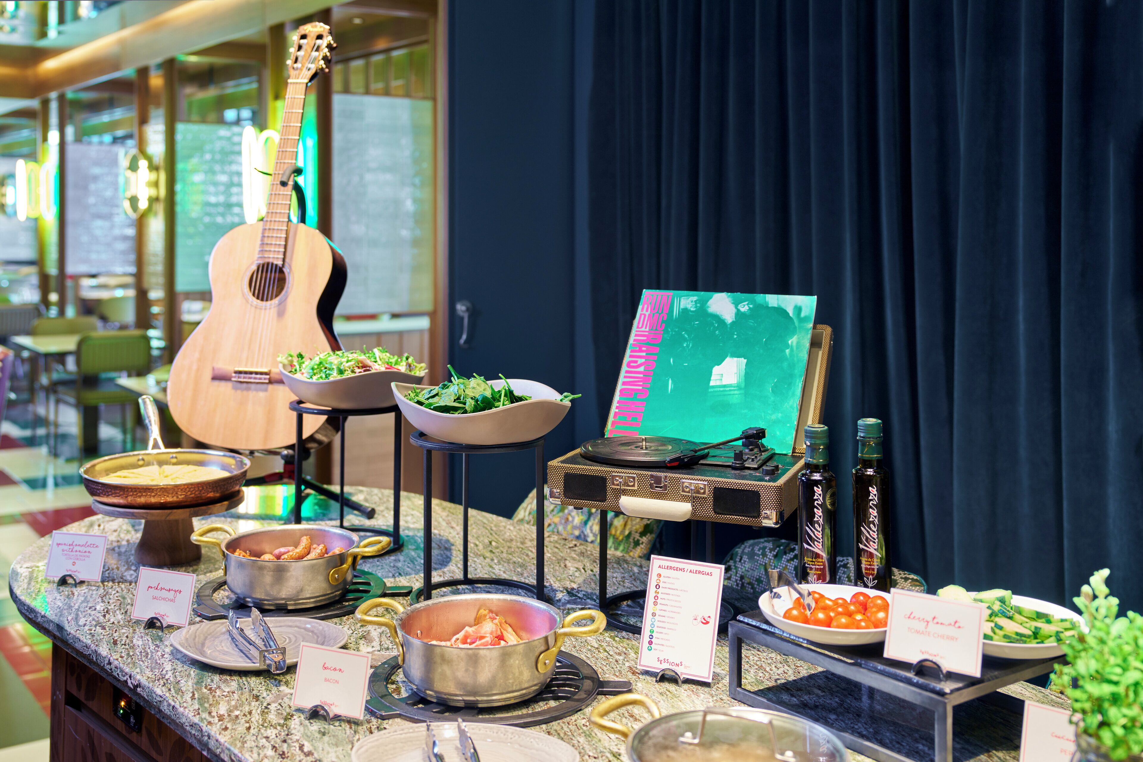 A buffet setup with various food items, a guitar, and a painting on a stand.