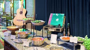 Montaje de bufé con diferentes alimentos, una guitarra y un cuadro sobre un soporte.