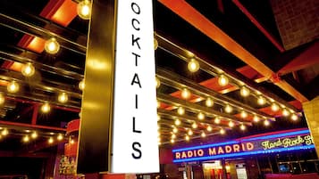 Eine Bar mit einem Schild für 'COCKTAILS' und einer Neonreklame für 'RADIO MADRID Hard Rock'.