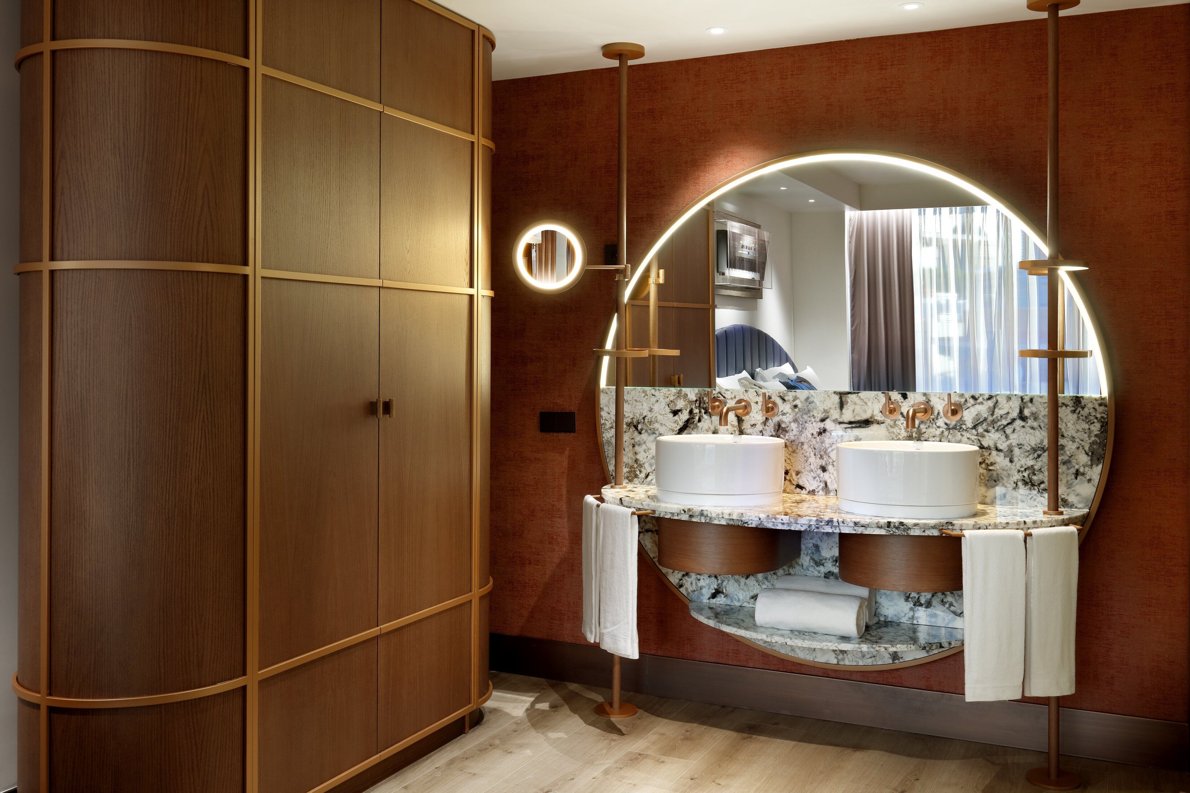 A modern bathroom with a wooden wardrobe, a vanity with two sinks, and a large mirror.