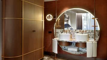A modern bathroom with a wooden wardrobe, a vanity with two sinks, and a large mirror.