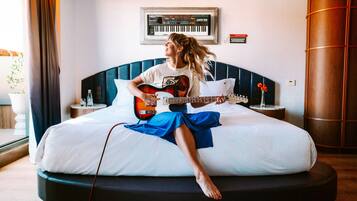 A person sitting on a bed playing an electric guitar.