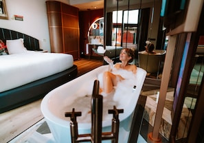 A modern hotel room with a large bed, a bathtub, and a seating area with a view of the city. - Hard Rock Hotel Madrid (Madrid)