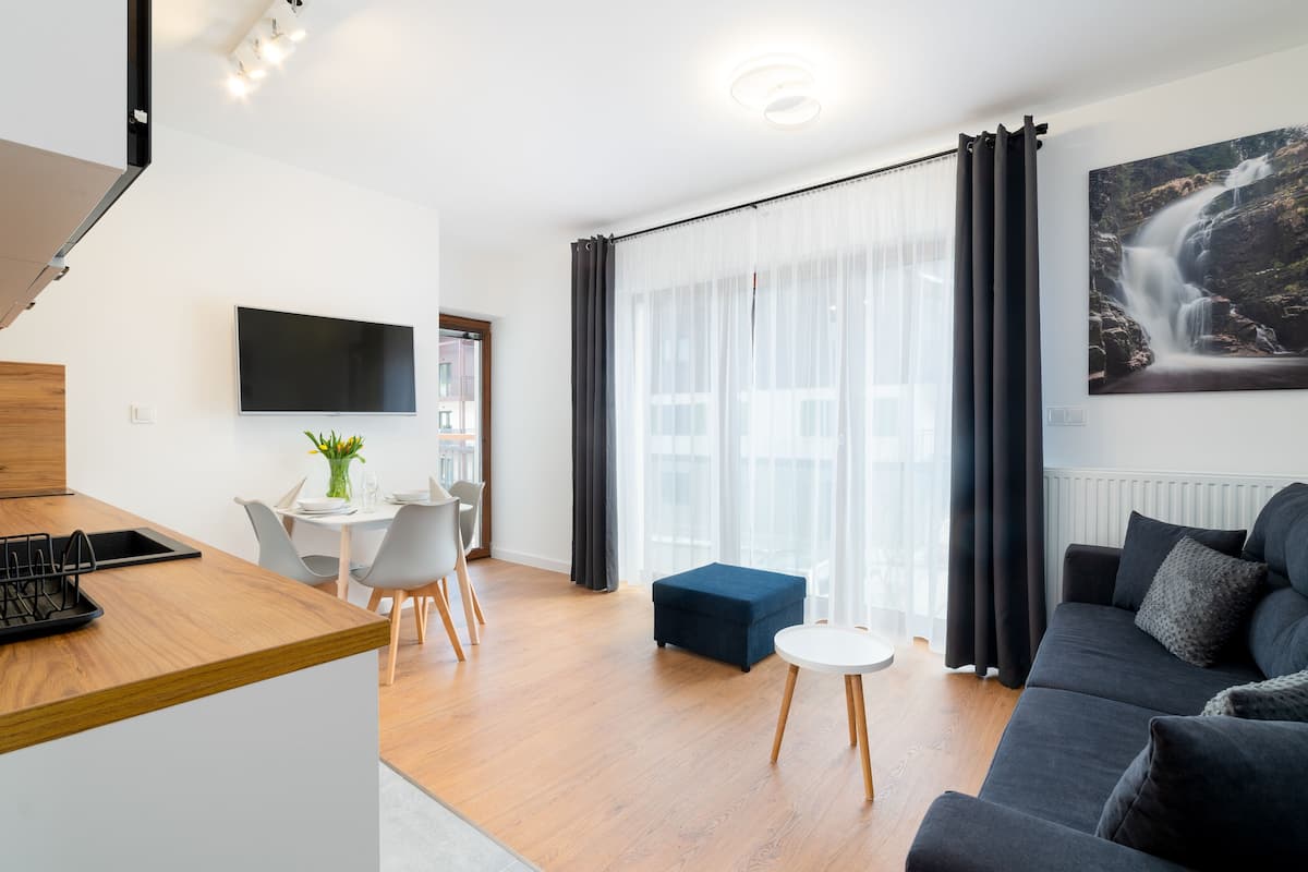 Un salon moderne avec un canapé, une table basse et un téléviseur fixé au mur.