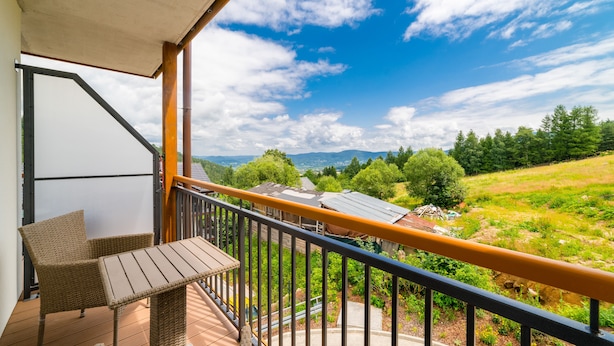 A balcony with wicker furniture and a view of a green landscape.