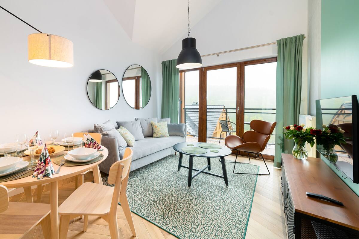 Un salon moderne avec un coin repas, de grandes fenêtres et un balcon offrant une vue dégagée.