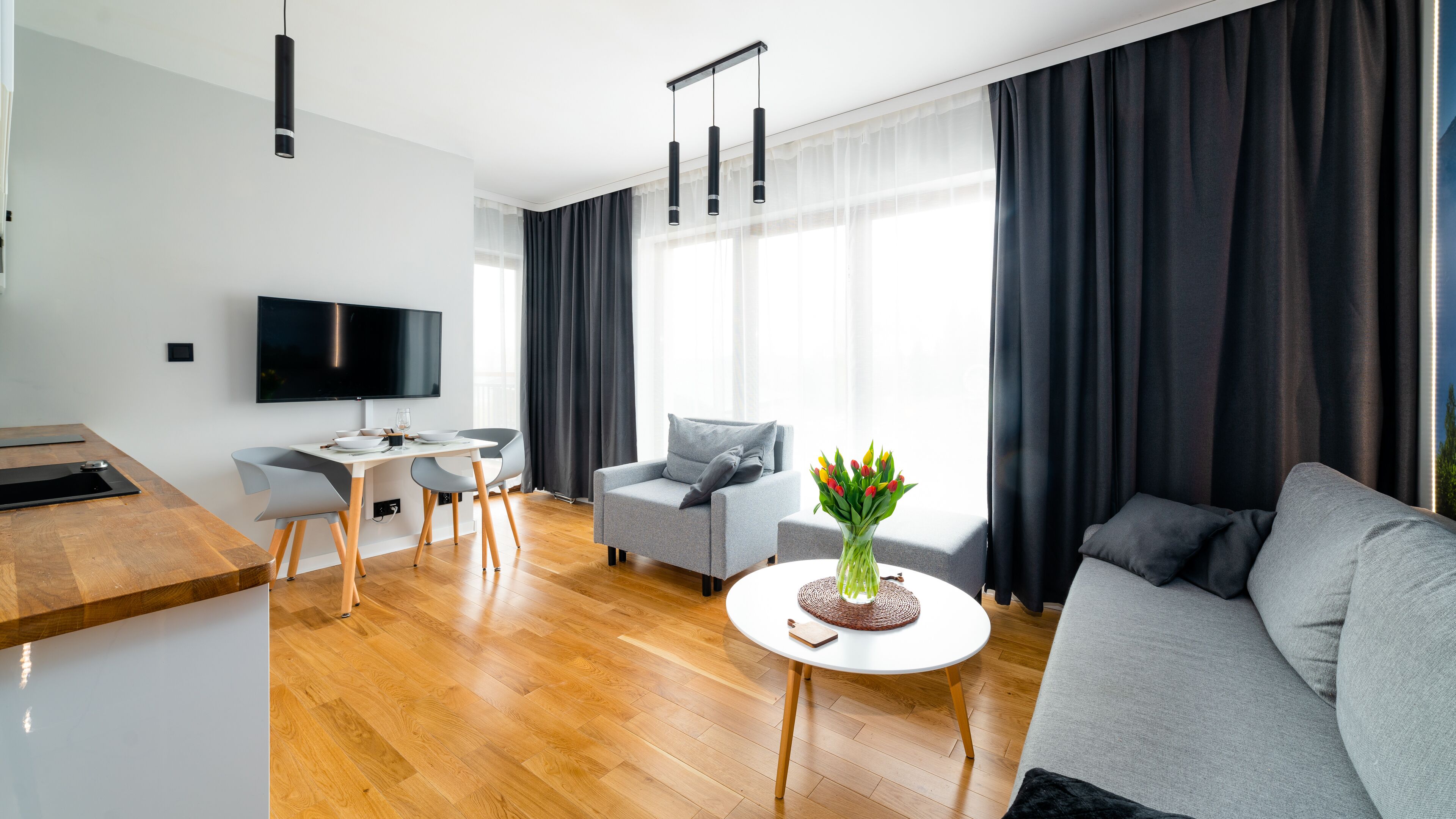 Een moderne woonkamer met een bank, een eettafel en een televisie.