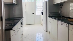 Eine moderne Küche mit weißen Schränken, einer schwarzen Arbeitsplatte, einem Kühlschrank und einem Spülbecken.