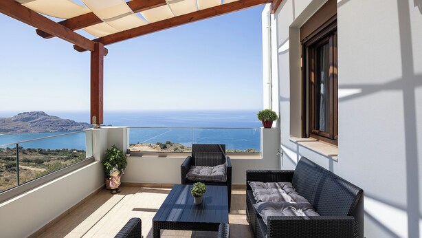 A balcony with wicker furniture, a potted plant, and a view of the sea. - Anastasia Villa, Libyan SeaViews with Heated Pool (Sellia, Rethymno)