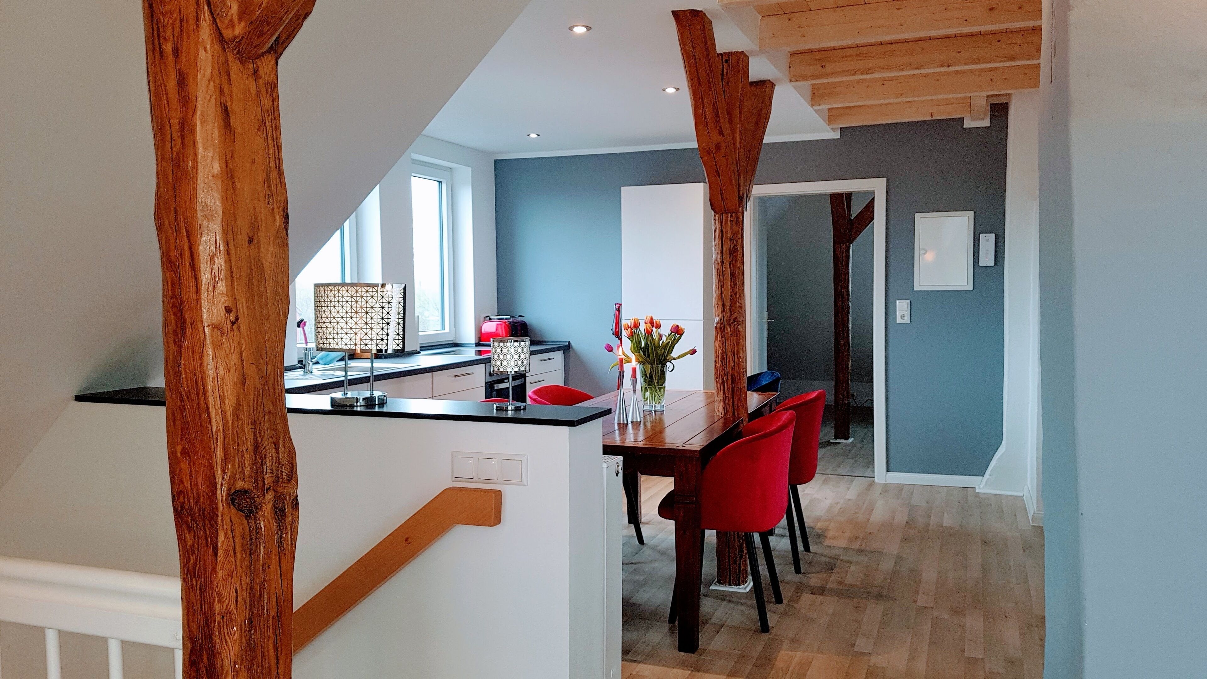 Una cocina moderna con una isla central, sillas rojas y una mesa de comedor.
