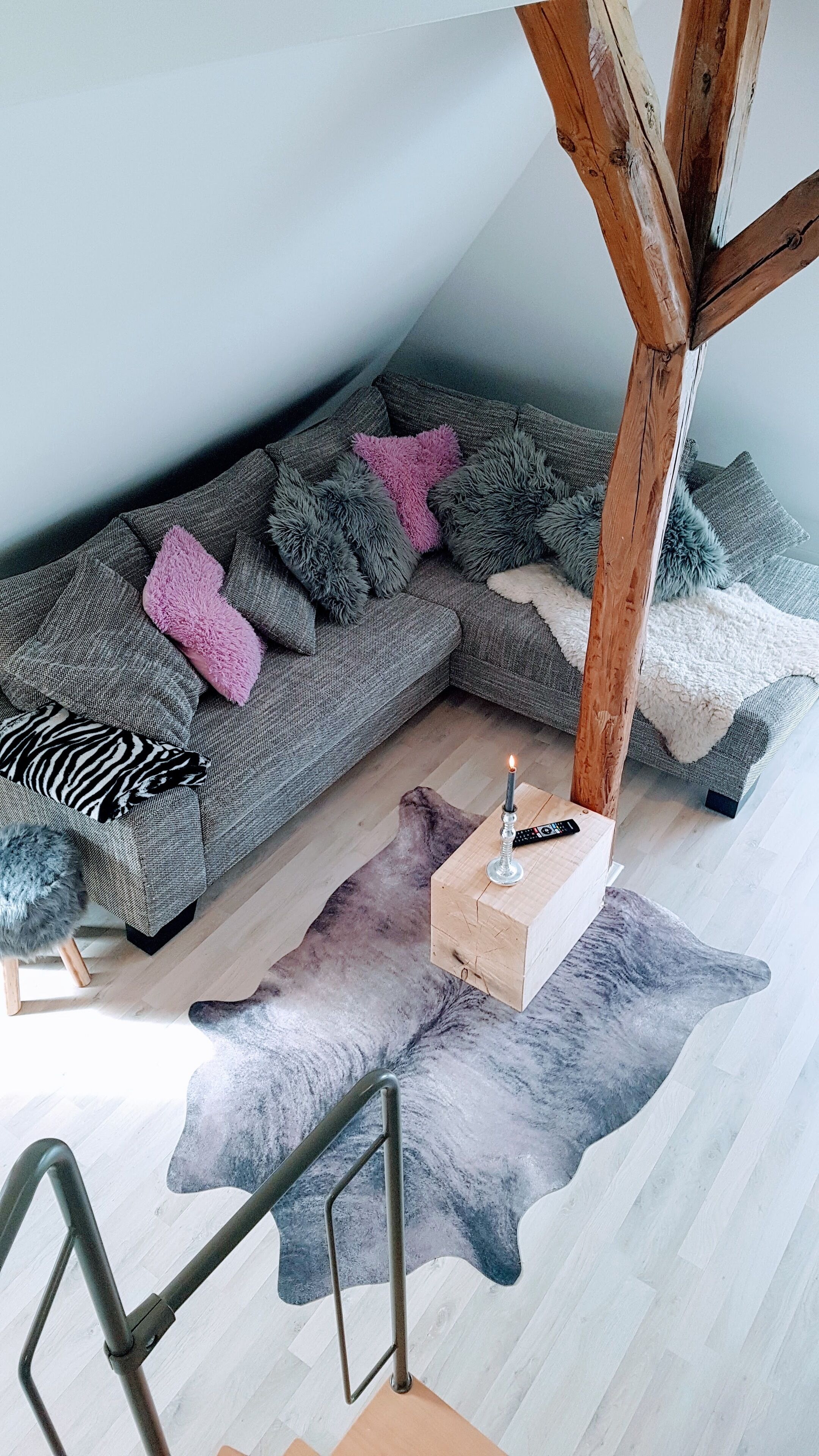 Una sala de estar acogedora con un sofá seccional gris, una mesa de centro de madera y una alfombra de piel única.